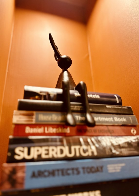 Stack of books with a black decorative airplane model on top, warm interior lighting