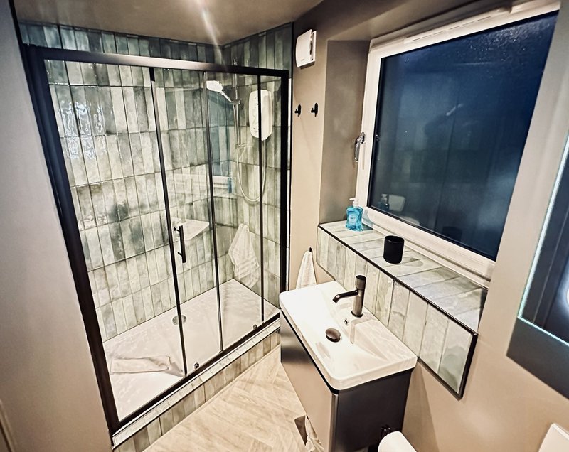 Modern bathroom with walk-in shower, vanity sink, and mirror