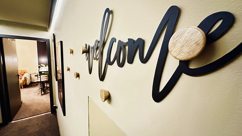 Hallway with cream walls, wooden door, and decorative black wall art with circular elements
