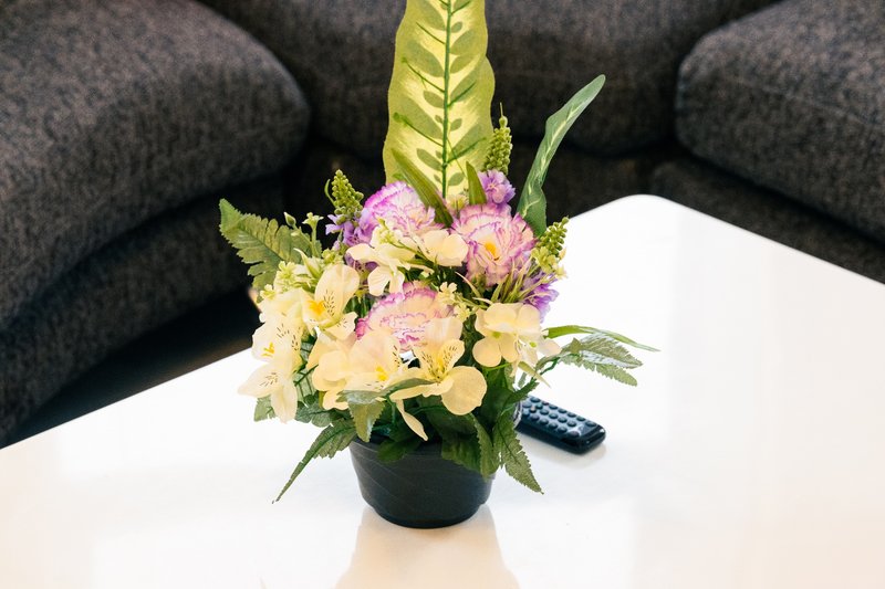 Gray upholstered sofa with floral arrangement and remote control on white table