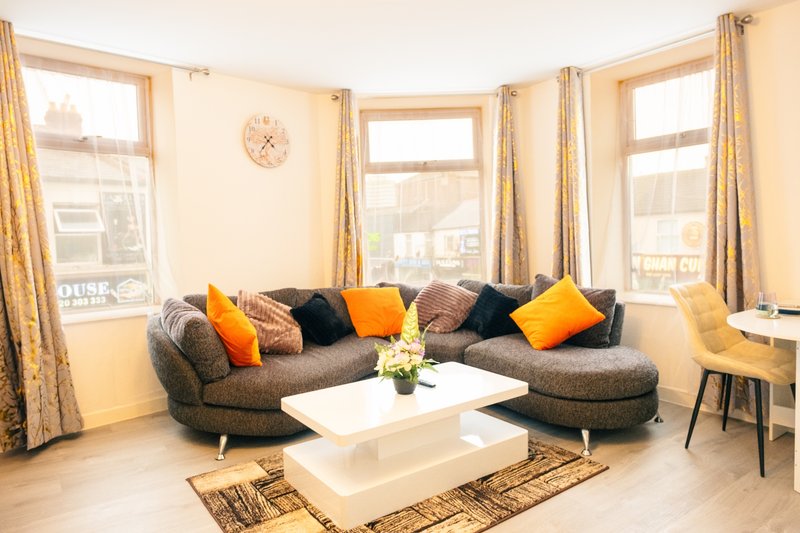 Modern living room with curved gray sofa, colorful cushions, white coffee table and large windows