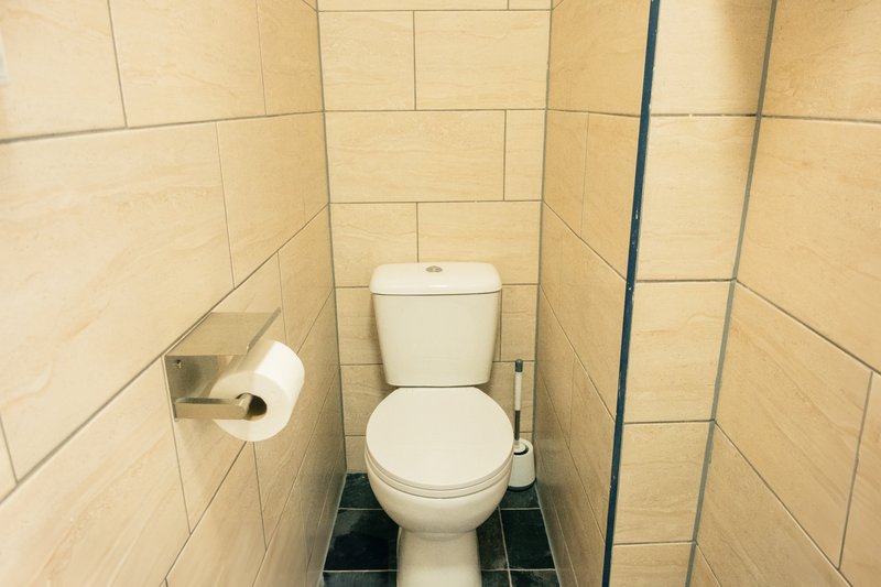 Small bathroom with toilet, cream tile walls, toilet roll holder and dark floor