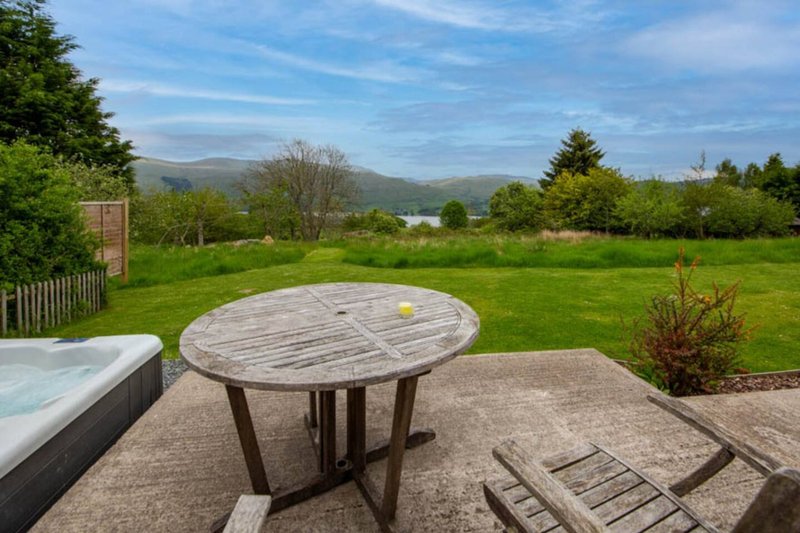 Spacious garden with patio, wooden table, lawn and mountain views