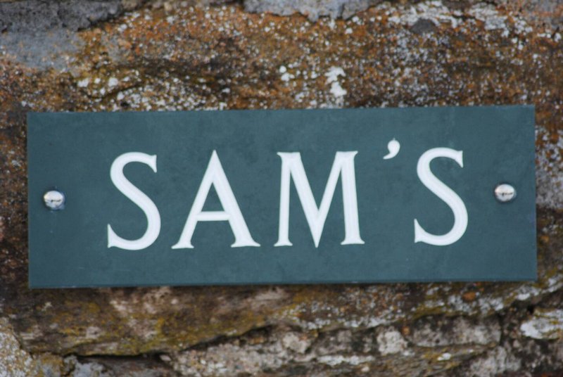 Property name plaque mounted on weathered brick wall exterior
