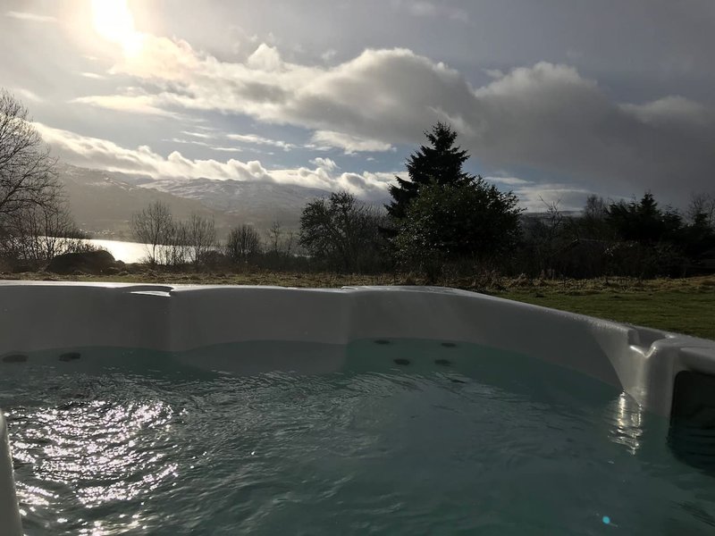 Outdoor swimming pool with countryside view, trees and cloudy sky in background
