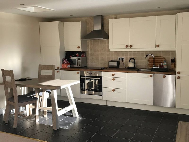 Modern kitchen with cream cabinets, black countertops, dining table and stainless steel appliances