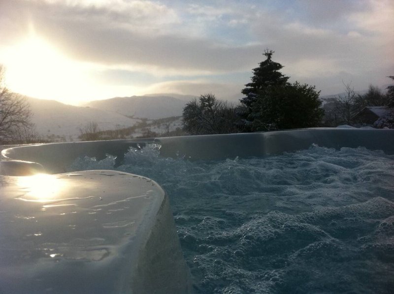 Outdoor hot tub with mountainous landscape and sunrise in background