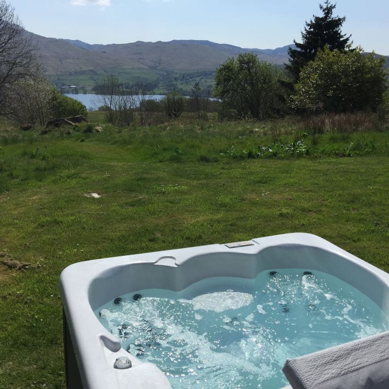 Hot tub with bubbling water in garden overlooking lake and mountains