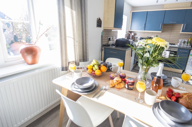 Modern kitchen and dining area with island table, place settings, fresh flowers and fruit