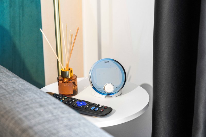 Bedside table with reed diffuser, remote control, and blue decorative device