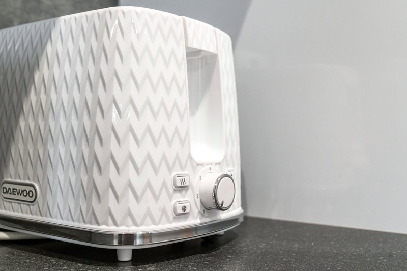 White patterned toaster with chrome base on dark countertop