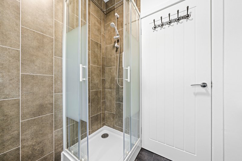 Modern bathroom with walk-in shower, tiled walls, white panelling and heated towel rail