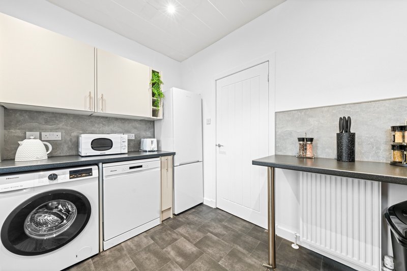 Modern laundry room with white cabinetry, washing machine, dryer and grey countertops