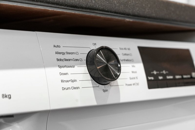 Close-up of washing machine control panel with dial and labeled buttons