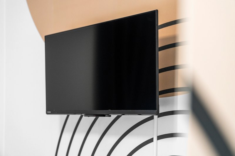 Wall-mounted flat-screen TV with cables against plain cream wall