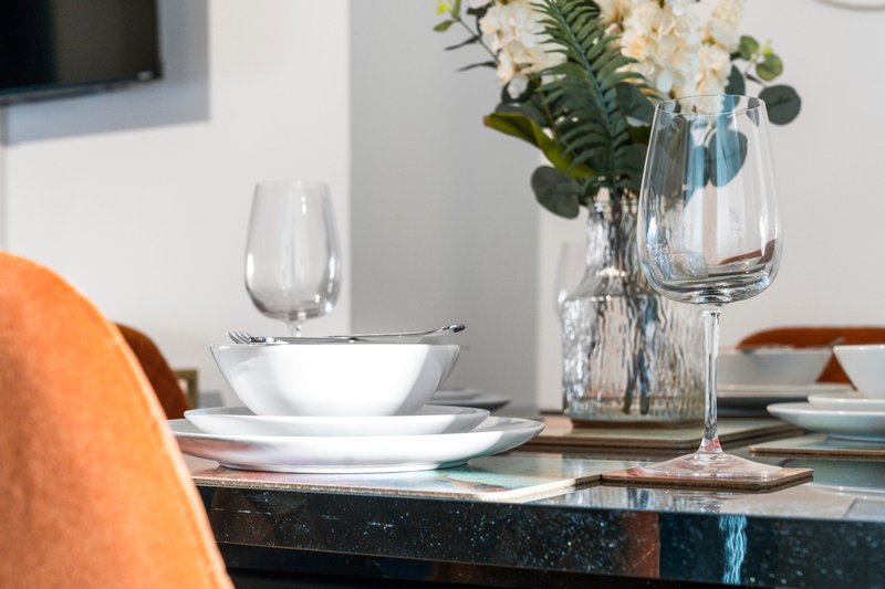 Dining table setting with place settings, glassware, and fresh white flowers in vase