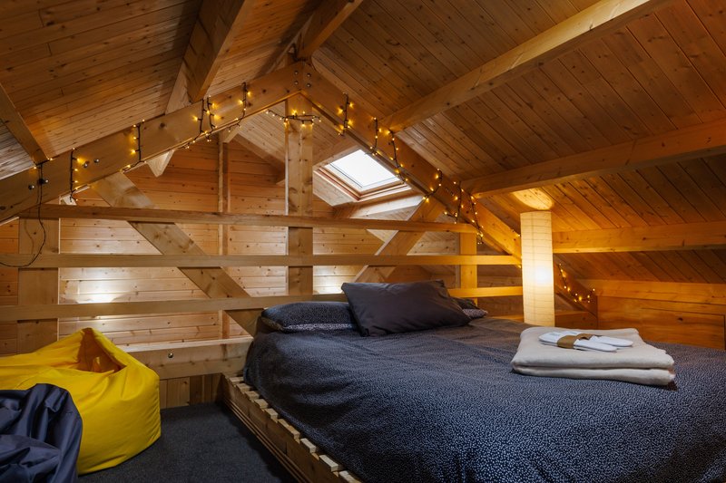 Wooden loft bedroom with double bed, skylight, exposed beams and yellow bean bag