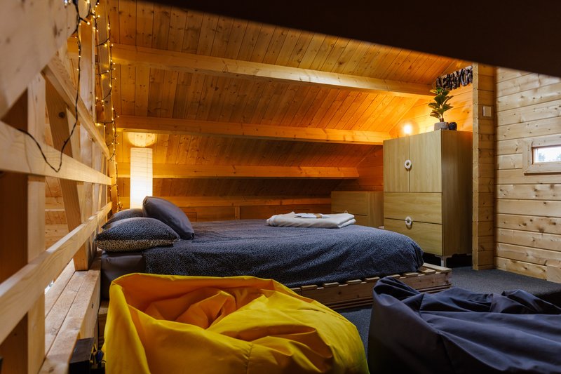 Cozy wooden bedroom with bunk bed, dark bedding, and yellow sleeping bag on floor