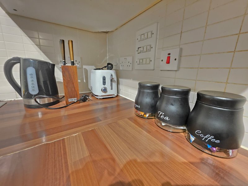 Kitchen counter with kettle, toaster, utensil holder, and labeled storage jars