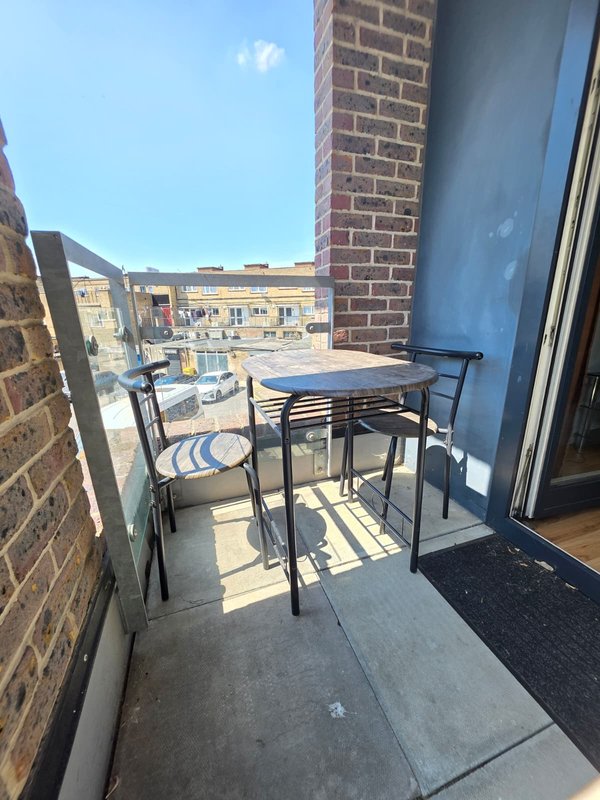 Small balcony with table, chairs and striped cushion overlooking urban street