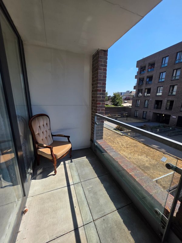 Balcony with upholstered chair, concrete floor, brick column, urban street view