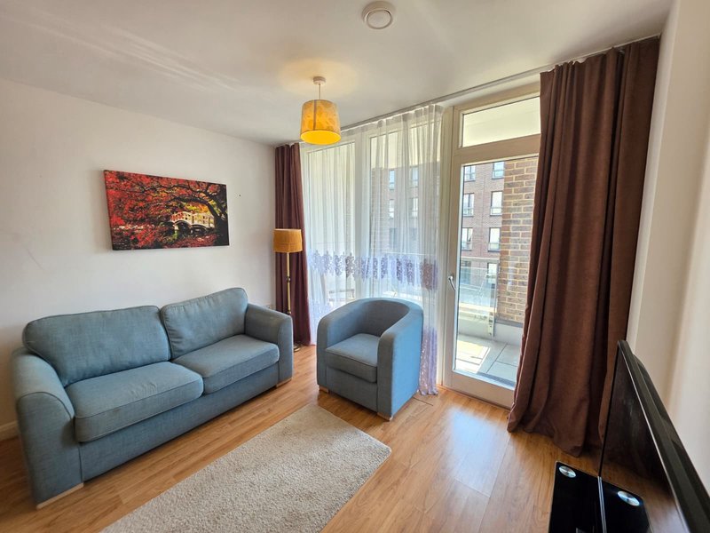Living room with blue sofa, armchair, wooden floor and city views from balcony