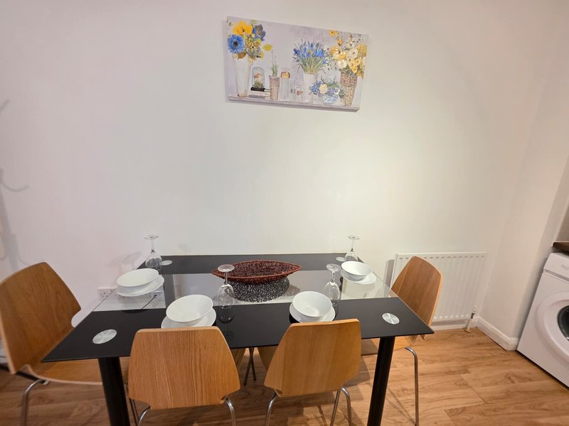 Dining area with black table, four wooden chairs, place settings, and wall decor