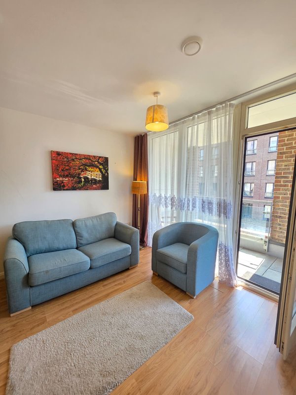 Modern living room with blue sofa, armchair, wooden floor and balcony access