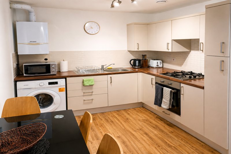 Modern kitchen with cream cabinets, wooden floor, dining table and integrated appliances