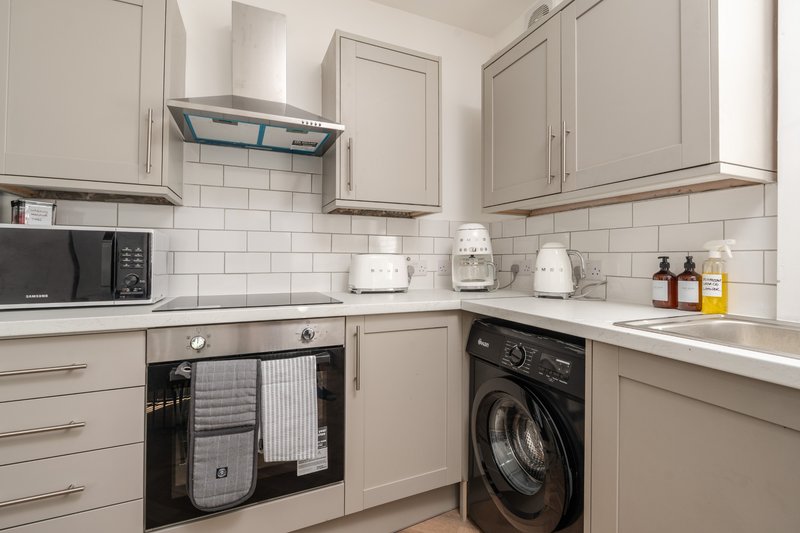 Modern kitchen with cream cabinets, white subway tile backsplash, black appliances and countertop accessories
