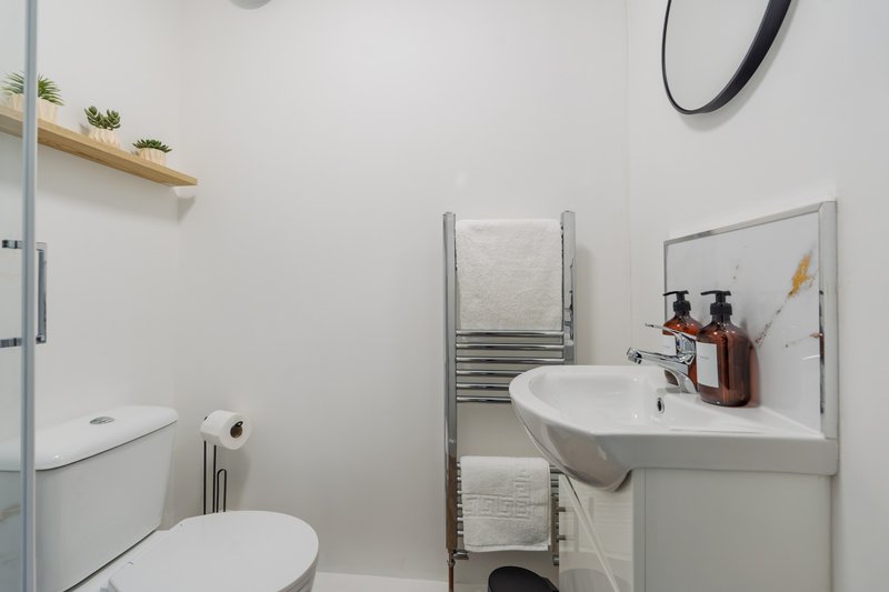 Modern bathroom with white sink, toilet, heated towel rail and mirror