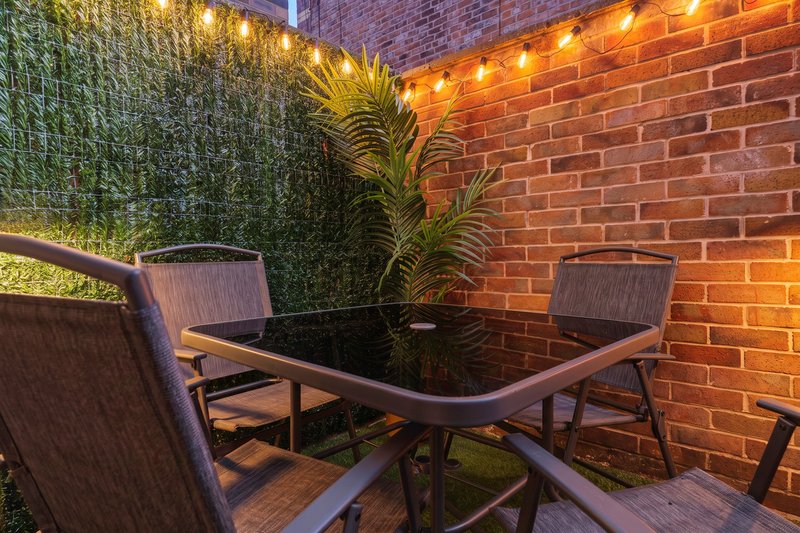 Outdoor patio with dining table, chairs, potted plants and warm string lighting