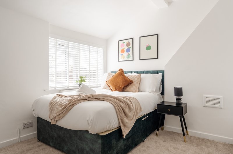 Bright bedroom with double bed, bedside table, framed wall art, and shuttered window