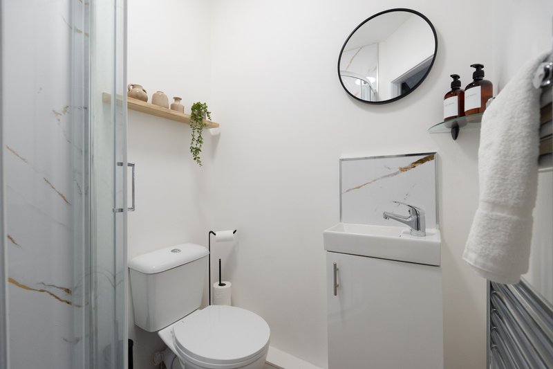 Modern bathroom with white toilet, sink, mirror, towel rail and shower enclosure