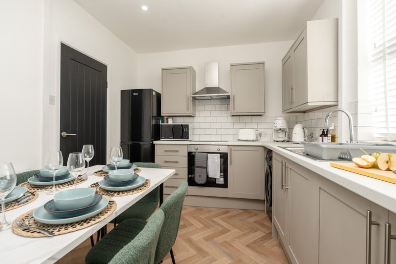 Modern kitchen with dining table, blue tableware, wooden flooring and stainless steel appliances