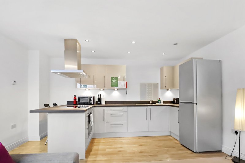 Modern kitchen with white cabinetry, stainless steel appliances, island counter and wooden flooring