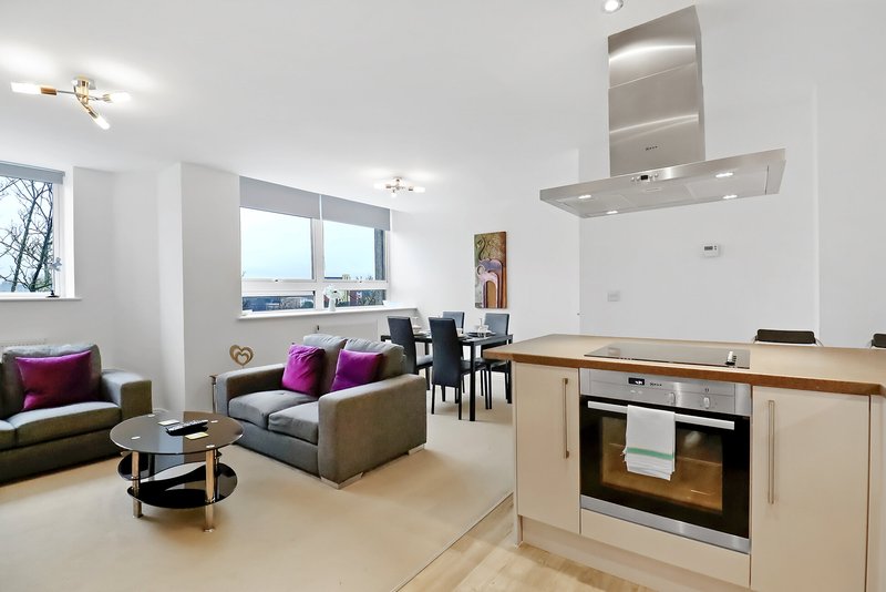 Open-plan living room and kitchen with sofa, dining table, built-in oven and sea views