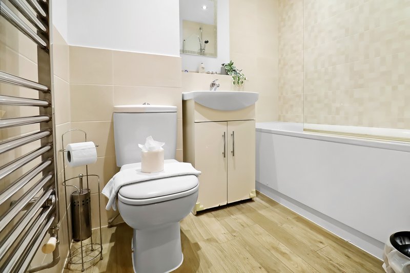 Modern bathroom with toilet, dual sinks, heated towel rail and wooden flooring