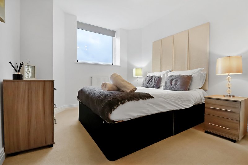 Modern bedroom with double bed, upholstered headboard, wooden nightstands and lamp