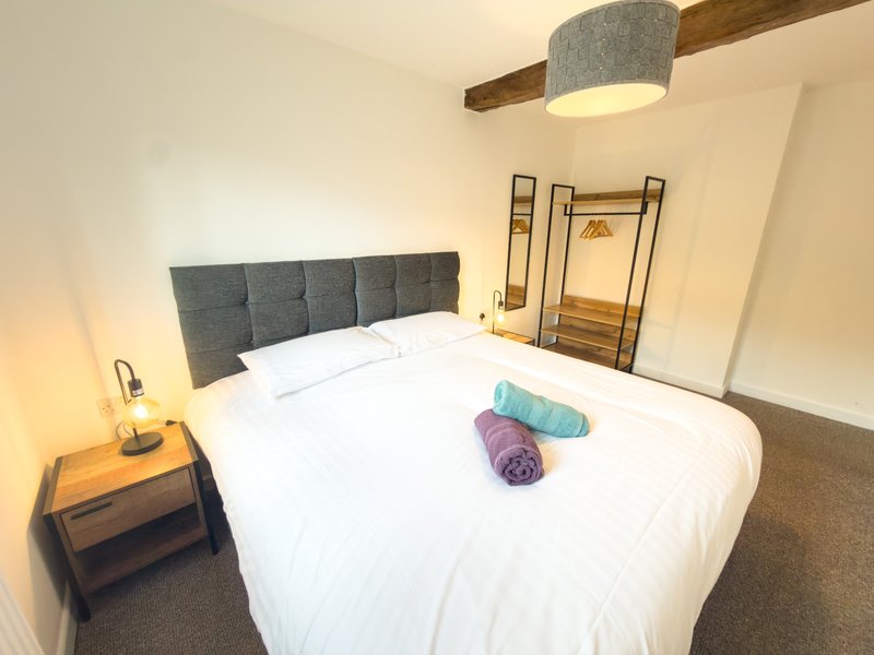 Modern bedroom with double bed, gray headboard, pendant light, and bedside table