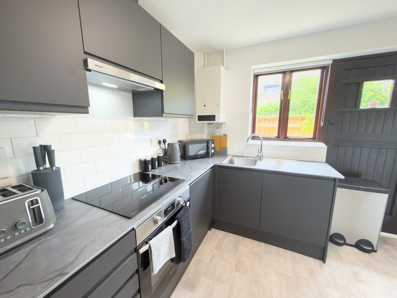Modern kitchen with dark grey cabinetry, white tile backsplash, stainless steel appliances and garden view