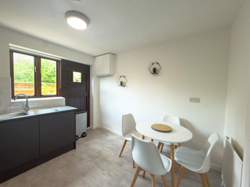 Modern kitchen and dining area with black cabinetry, round white table, and garden view