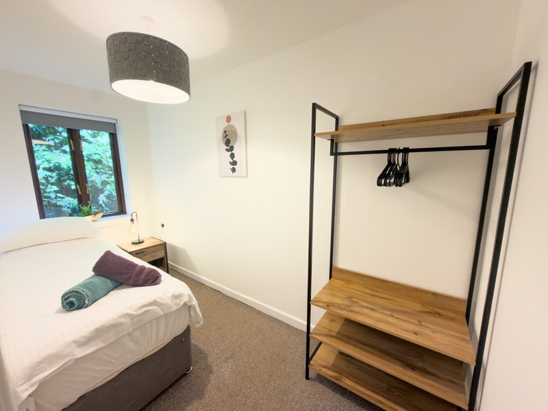 Modern bedroom with double bed, hanging rail wardrobe, ceiling lamp and window