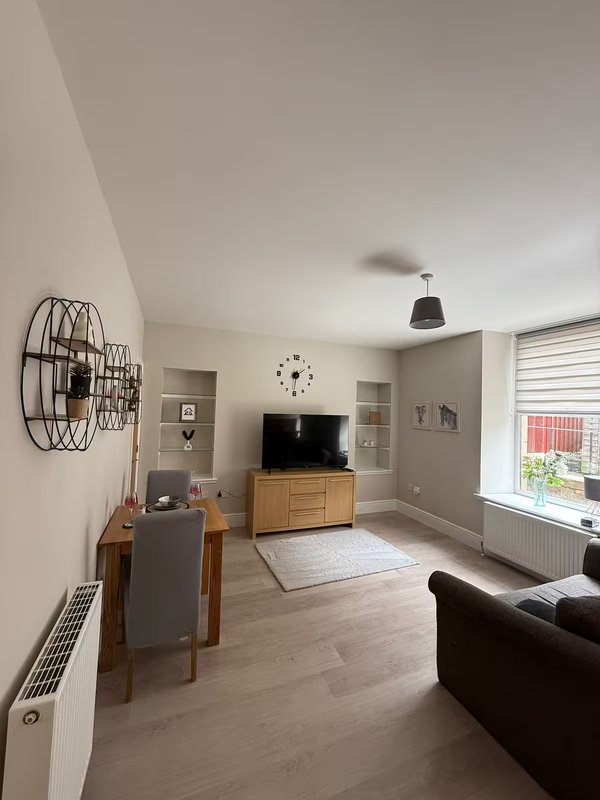 Bright living room with wooden dining table, TV stand, black sofa and pendant light