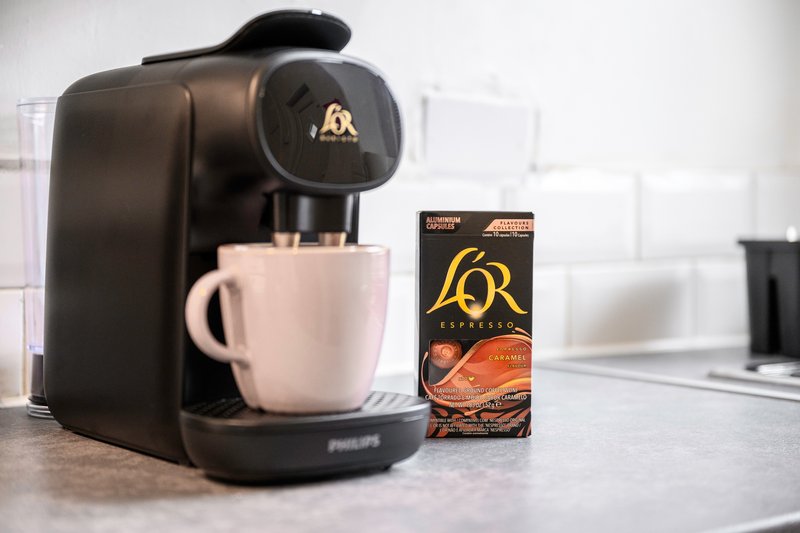Kitchen counter with black coffee machine, white mug, and coffee pod box