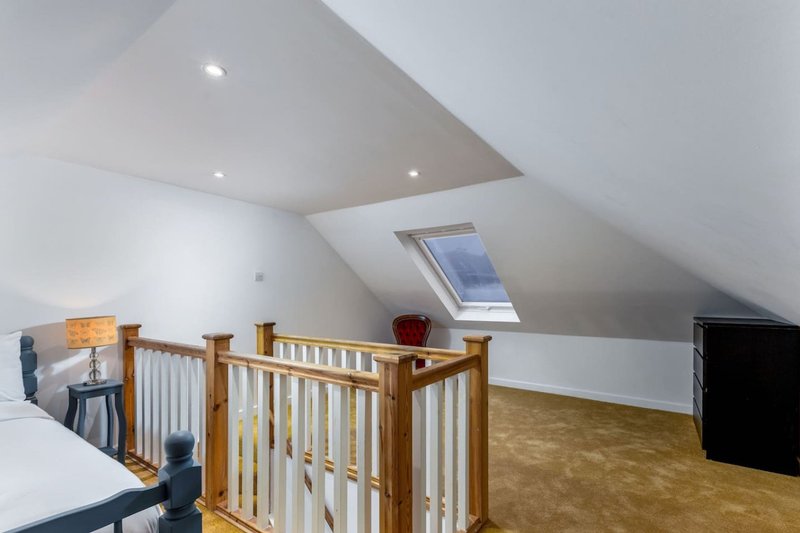 Bright attic bedroom with wooden crib, sloped ceiling, skylight and cork flooring
