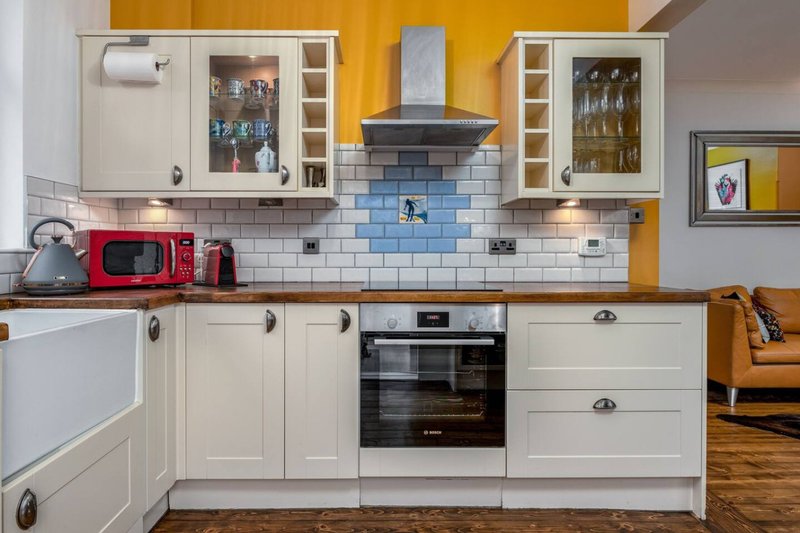 Modern kitchen with cream cabinets, blue subway tile backsplash, yellow walls and stainless steel appliances