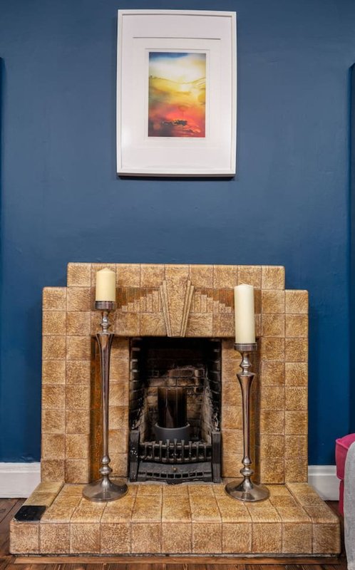 Blue living room with fireplace, framed sunset artwork above, and decorative candles