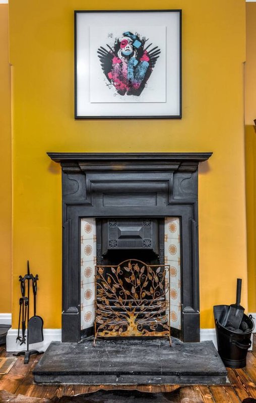 Bold yellow living room with black fireplace, framed abstract art above mantelpiece