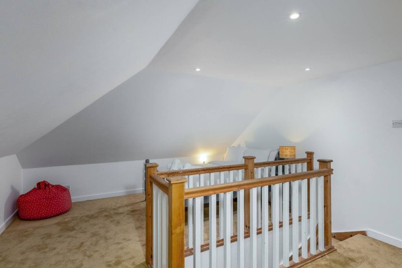 Attic nursery room with wooden crib, red bean bag, recessed lighting and sloped ceiling